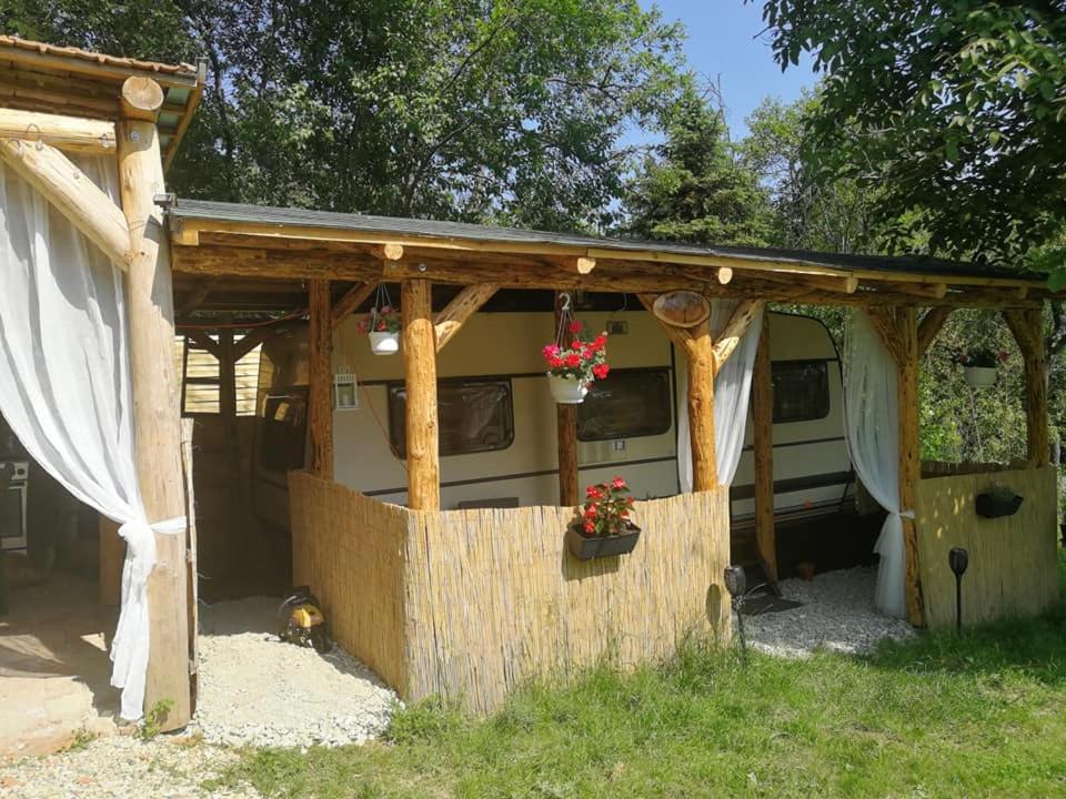 awning of a caravan with a fence and flowers at Őrségi Nomád-Lak Nomád 1 in Kercaszomor