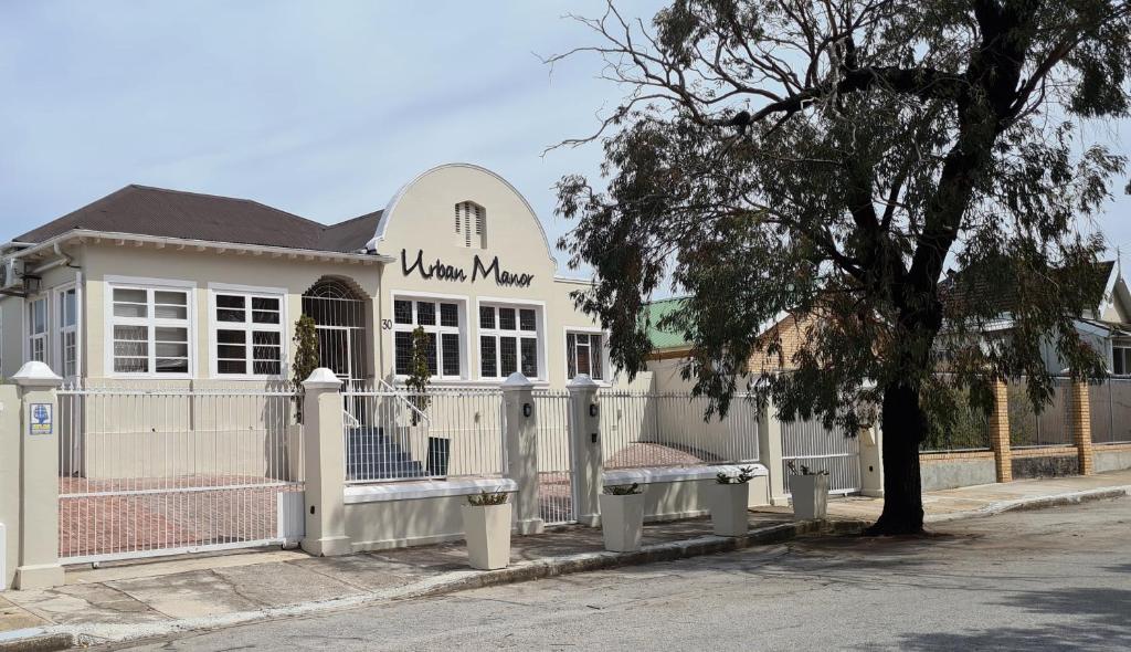 a white building with benches in front of a fence at Urban Manor in Port Elizabeth