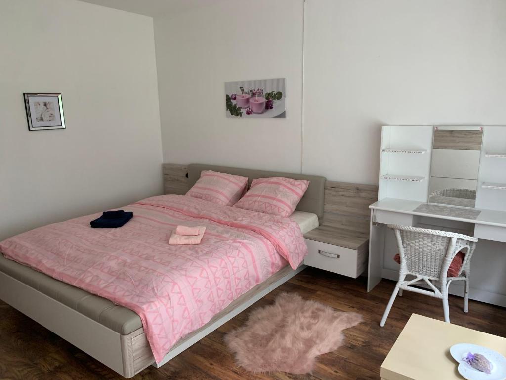 een slaapkamer met een bed met roze lakens en een bureau bij House Bastogne in Bastenaken