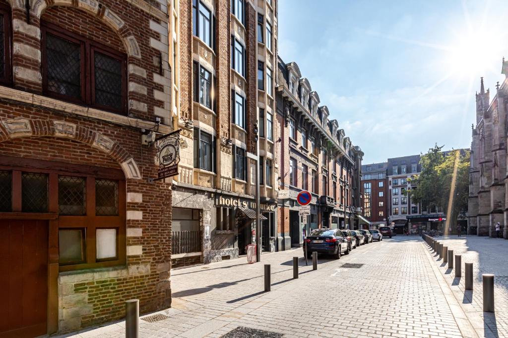 a brick building on a street with cars parked at Hôtel Saint Maurice in Lille