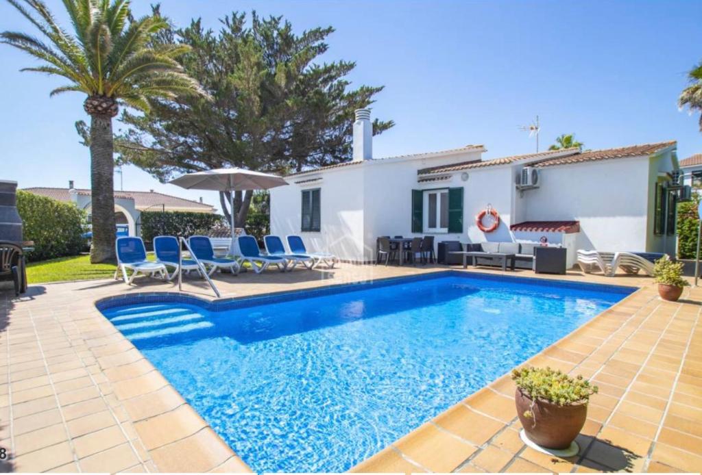 a villa with a swimming pool in front of a house at Villa Regina in Cala en Bosc
