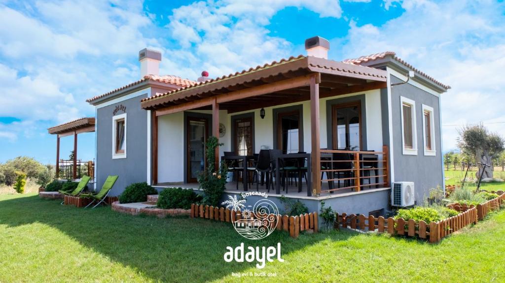 a small house with a porch and a lawn at Adayel Bagevi & Butik Otel in Bozcaada