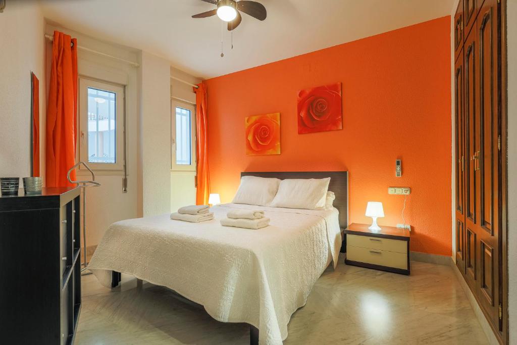 a bedroom with orange walls and a bed with towels on it at Apartamentos Alameda del Tajo I Parquing Centro in Ronda