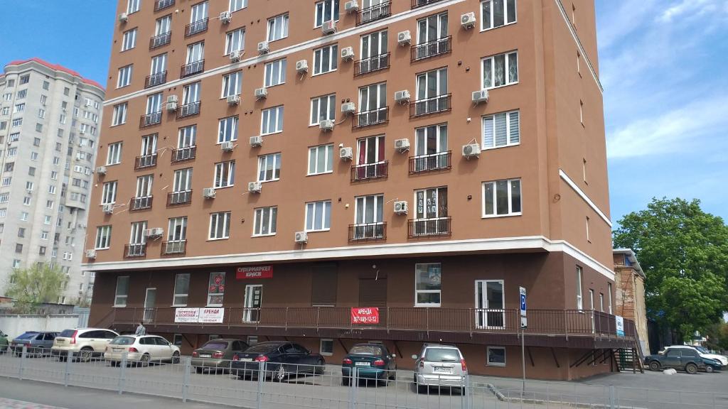 duży brązowy budynek z samochodami zaparkowanymi przed nim w obiekcie Эко студия на Южном вокзале w Charkowie