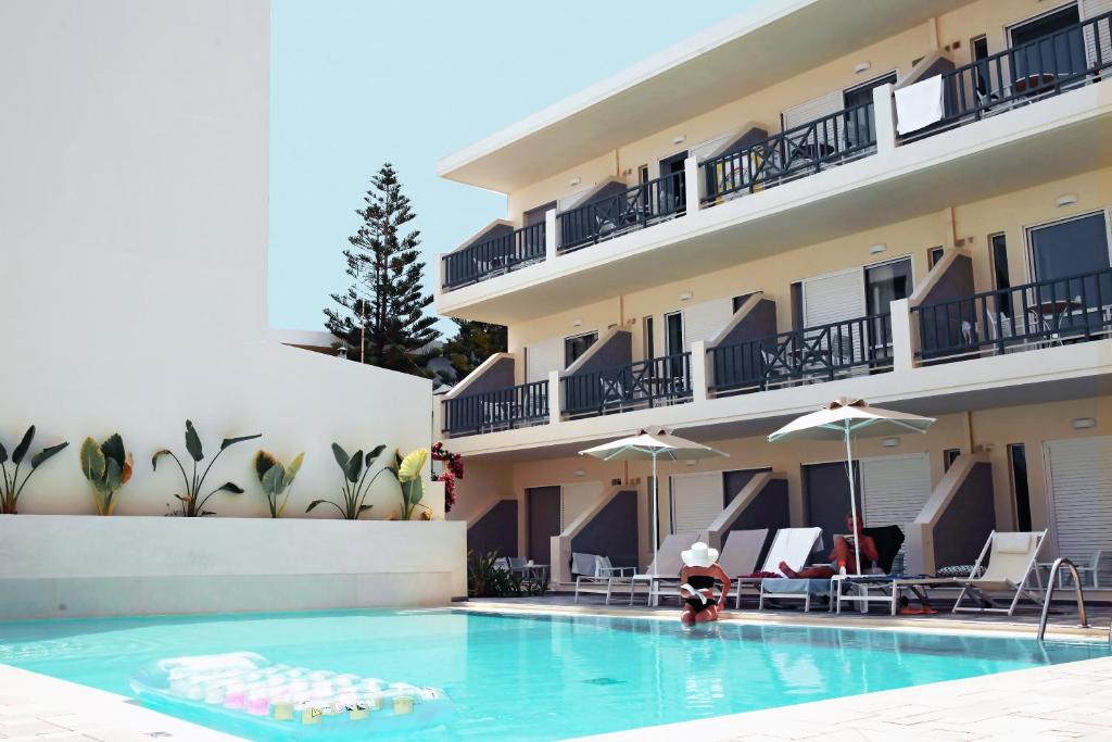 un hotel con piscina frente a un edificio en Melitti Hotel, en Rethymno