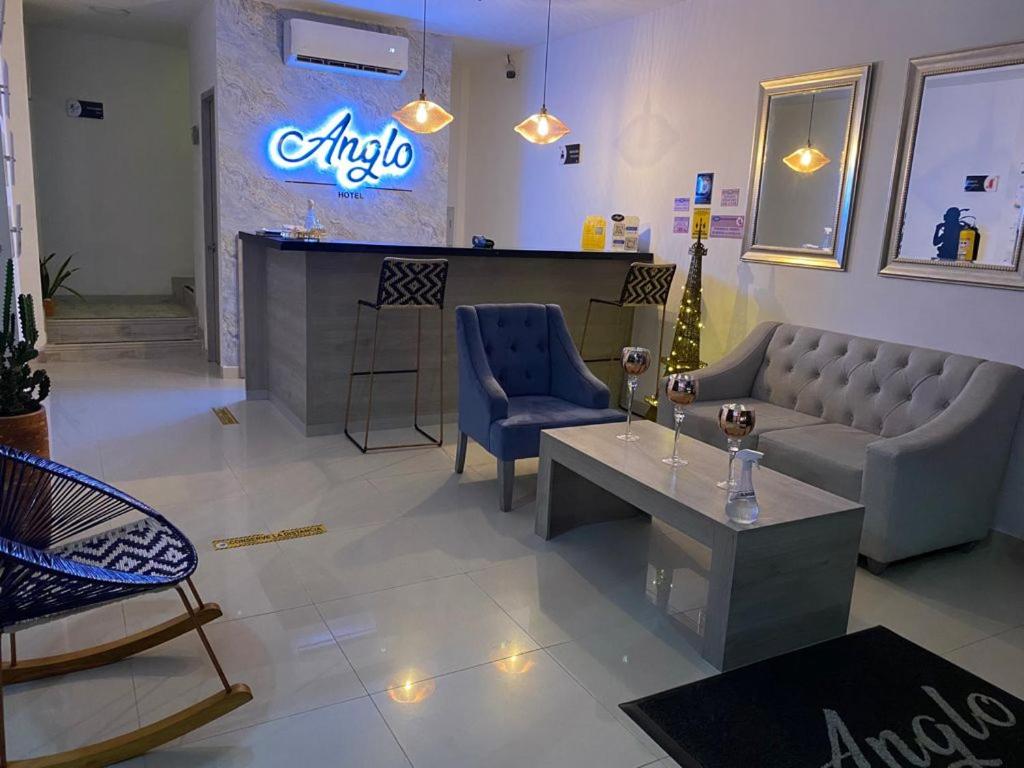 um átrio com um sofá, uma mesa e um bar em Hotel Anglo em Apartadó