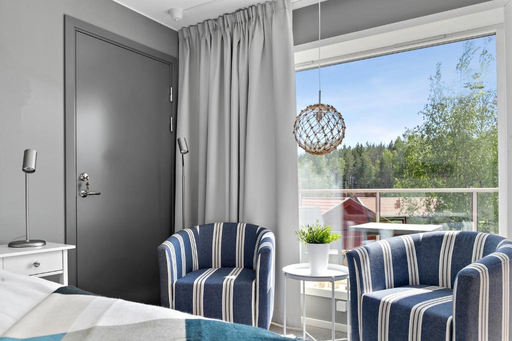 a bedroom with two chairs and a bed and a window at Skärgårdsbyn Hotell in Sankt Anna