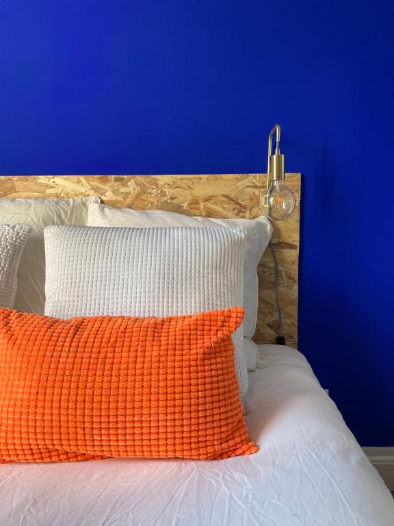 an orange pillow on a bed with a blue wall at Studio design Bleu Alpin in Le Mont-Dore