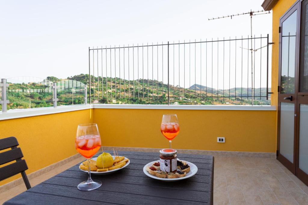 un tavolo con 2 bicchieri da vino e cibo su un balcone di La Dimora Di Segesta B&B a Calatafimi