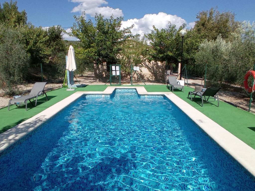 una piscina con due sedie e un ombrellone di El Valle de Yeste a Yeste