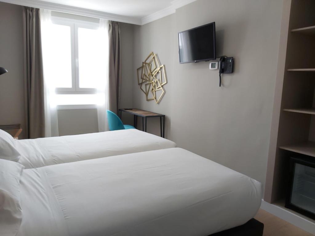 a hotel room with two beds and a tv at Micampus Burgos Centro in Burgos