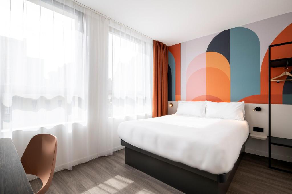 a bedroom with a white bed and a colorful wall at B&B HOTEL Antwerpen Centrum in Antwerp