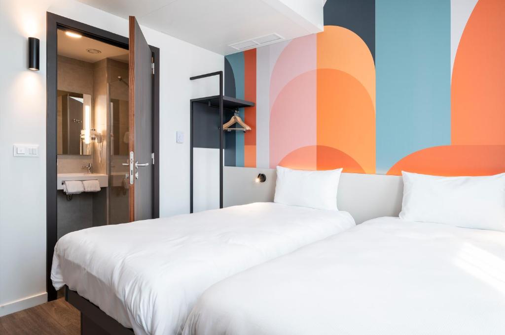 a bedroom with two beds and a colorful wall at B&B HOTEL Antwerpen Centrum in Antwerp