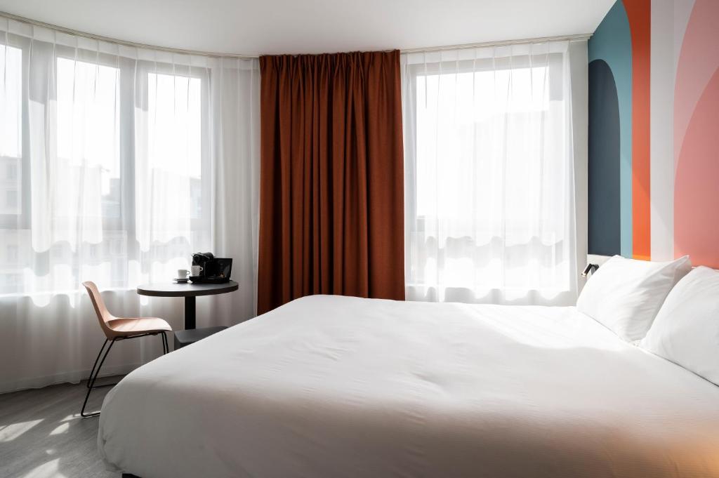 a bedroom with a large white bed and a table at B&B HOTEL Antwerpen Centrum in Antwerp