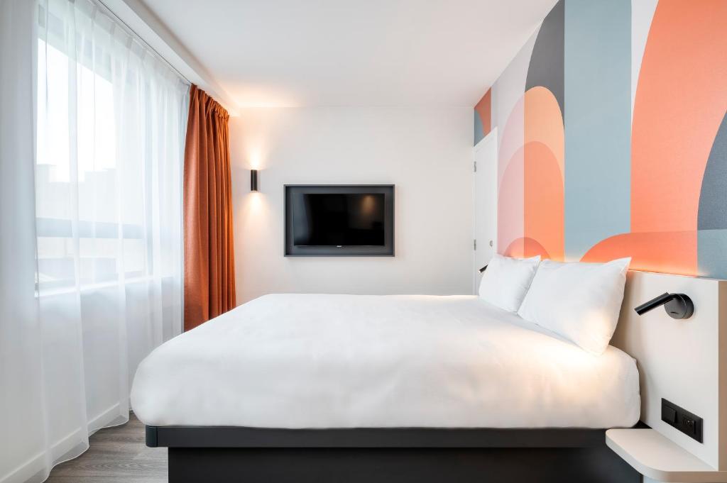 a hotel room with a white bed and a tv at B&B HOTEL Antwerpen Centrum in Antwerp