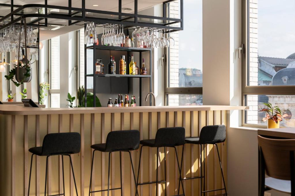 a bar with black stools in a room with windows at B&B HOTEL Antwerpen Centrum in Antwerp