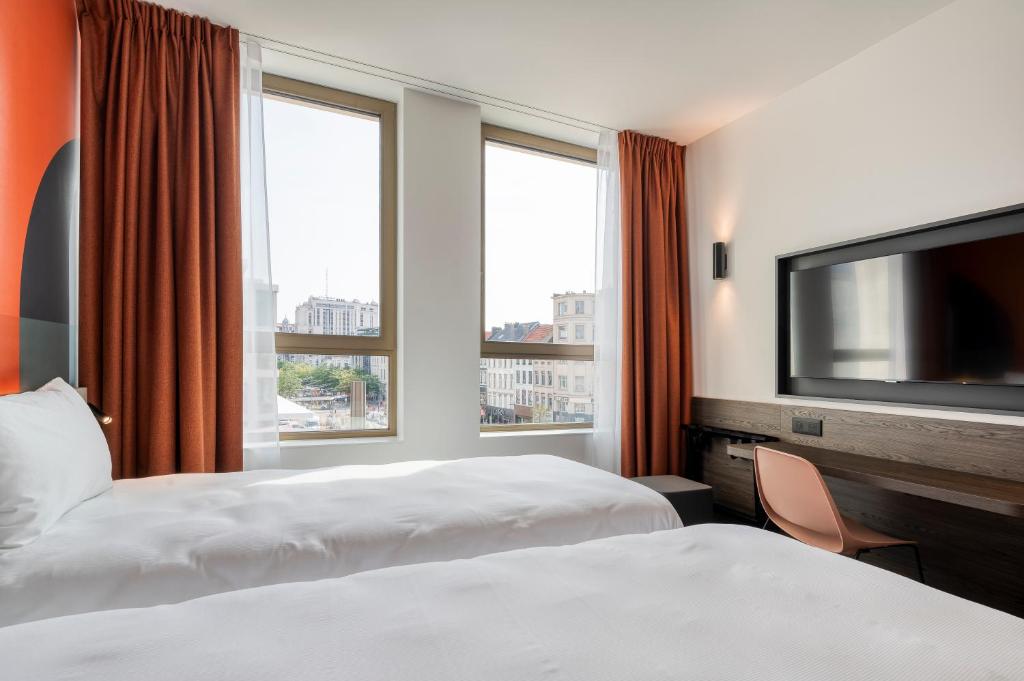 a hotel room with two beds and a flat screen tv at B&B HOTEL Antwerpen Centrum in Antwerp