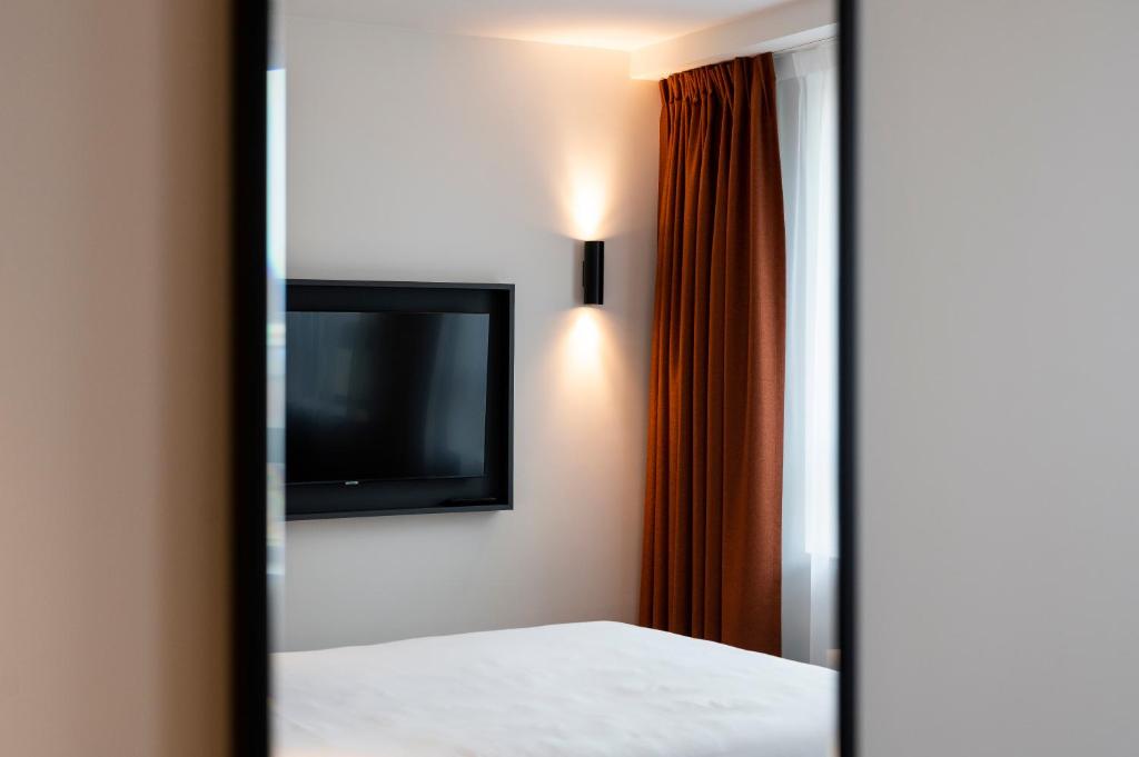 a room with a bed and a tv and a mirror at B&B HOTEL Antwerpen Centrum in Antwerp
