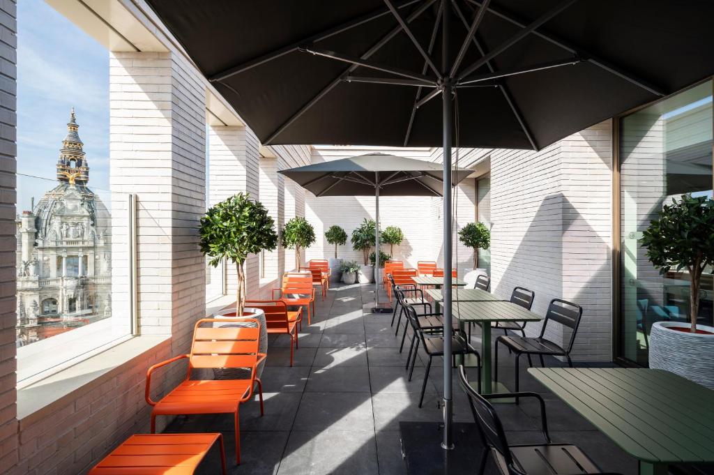 an outdoor patio with tables and chairs and an umbrella at B&B HOTEL Antwerpen Centrum in Antwerp