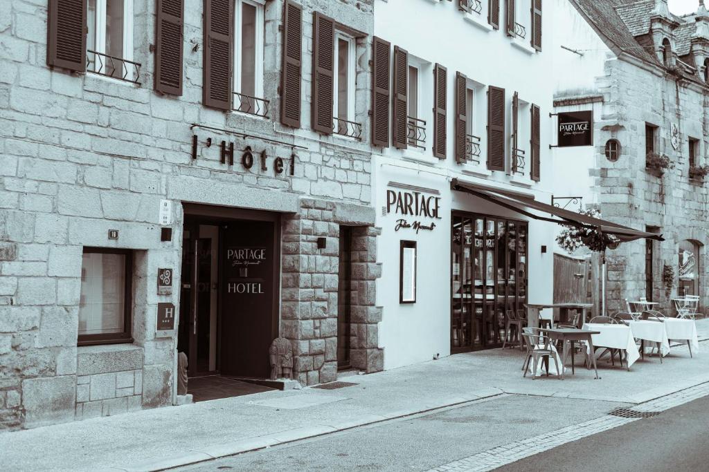 a building with a table and chairs on a street at Les Voyageurs in Saint-Renan