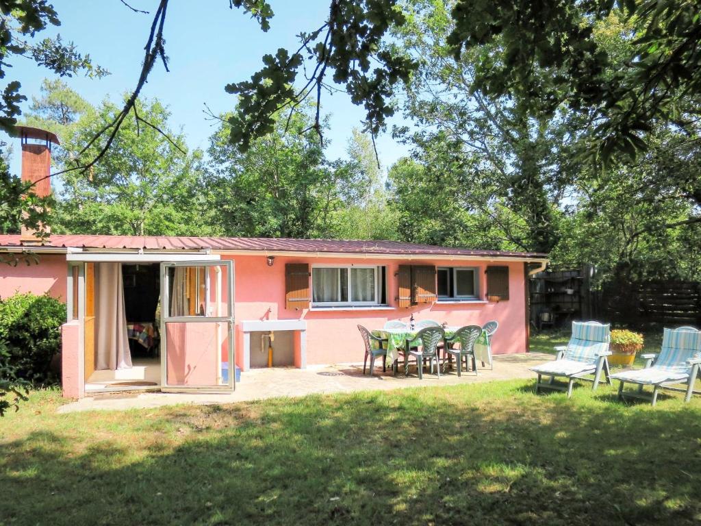 une maison rose avec une table et des chaises dans une cour dans l'établissement Holiday Home Castagney by Interhome, à Gaillan-en-Médoc