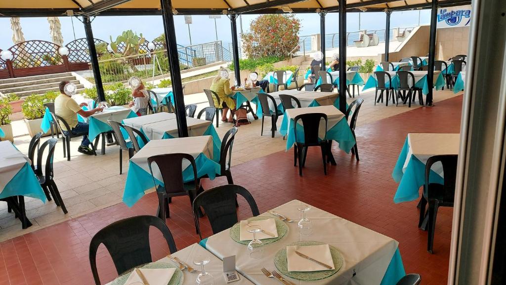 um restaurante com mesas e cadeiras com pessoas sentadas em Albergo La Lampara em Deiva Marina