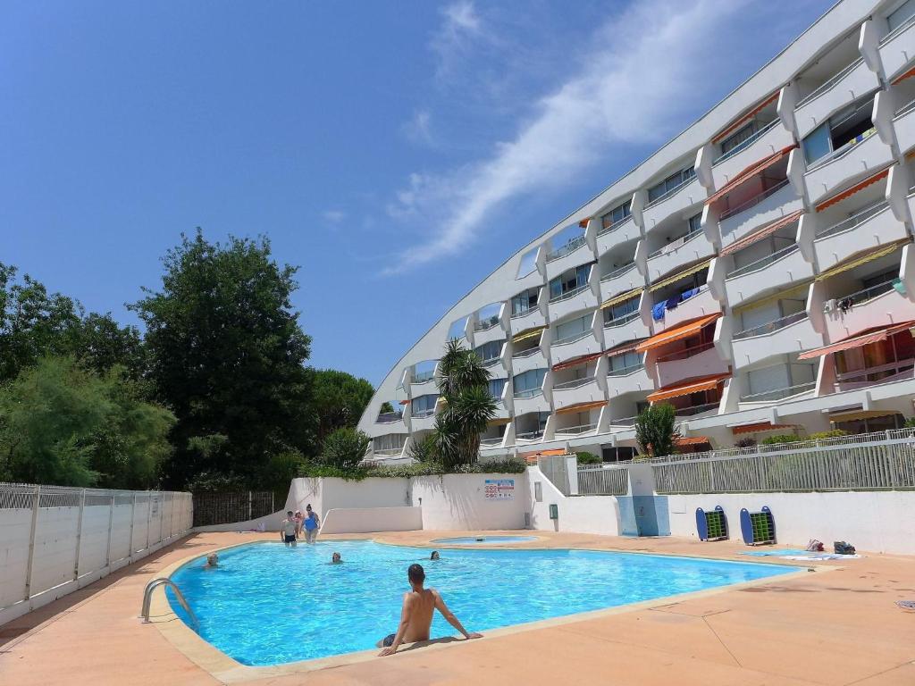 a man in a swimming pool in front of a building at Studio du Parc I by Interhome in La Grande Motte