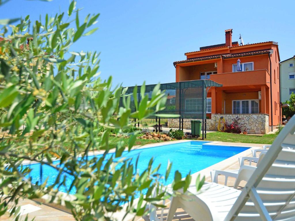 a swimming pool with two chairs and a house at Holiday Home Marko by Interhome in Filipac
