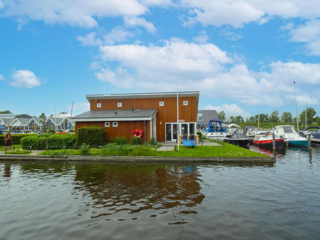 een gebouw naast een waterlichaam met boten bij Holiday Home De Meerparel by Interhome in Uitgeest