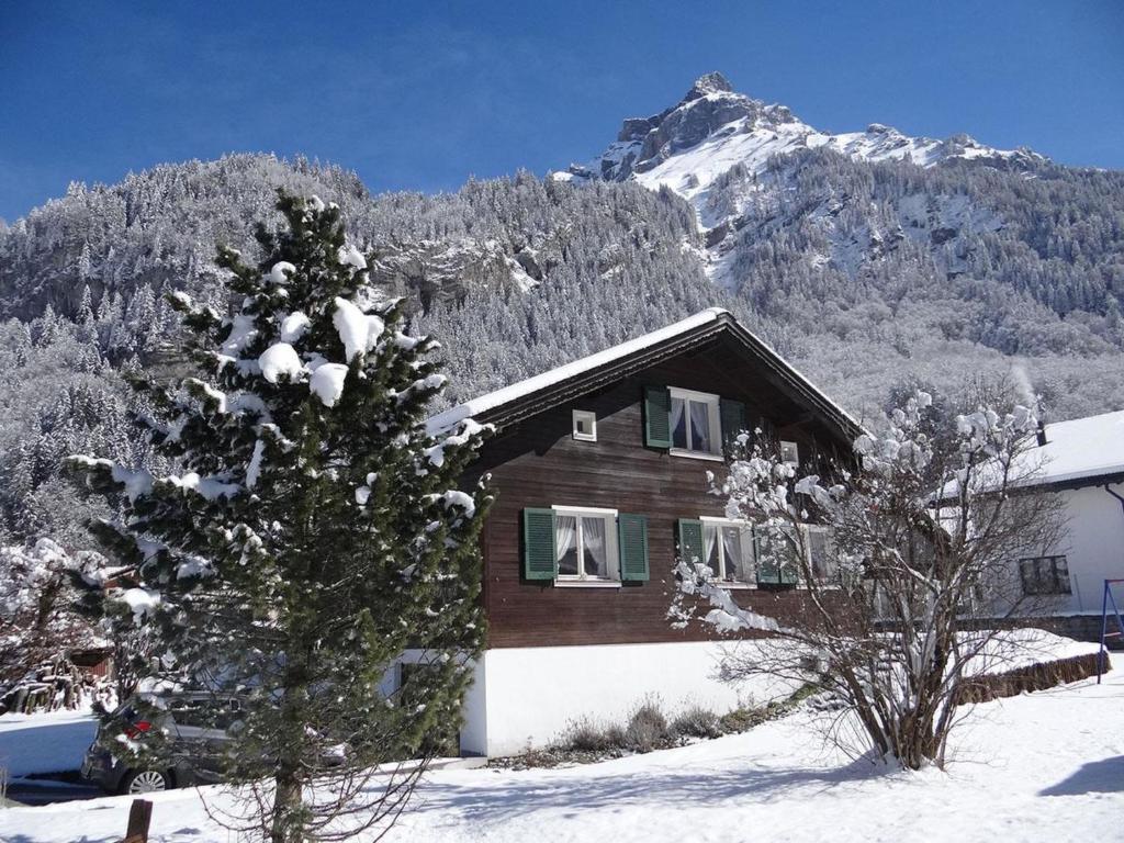 ein Haus im Schnee mit einem schneebedeckten Berg in der Unterkunft Apartment Chalet Fluegärtli by Interhome in Gerschnialp