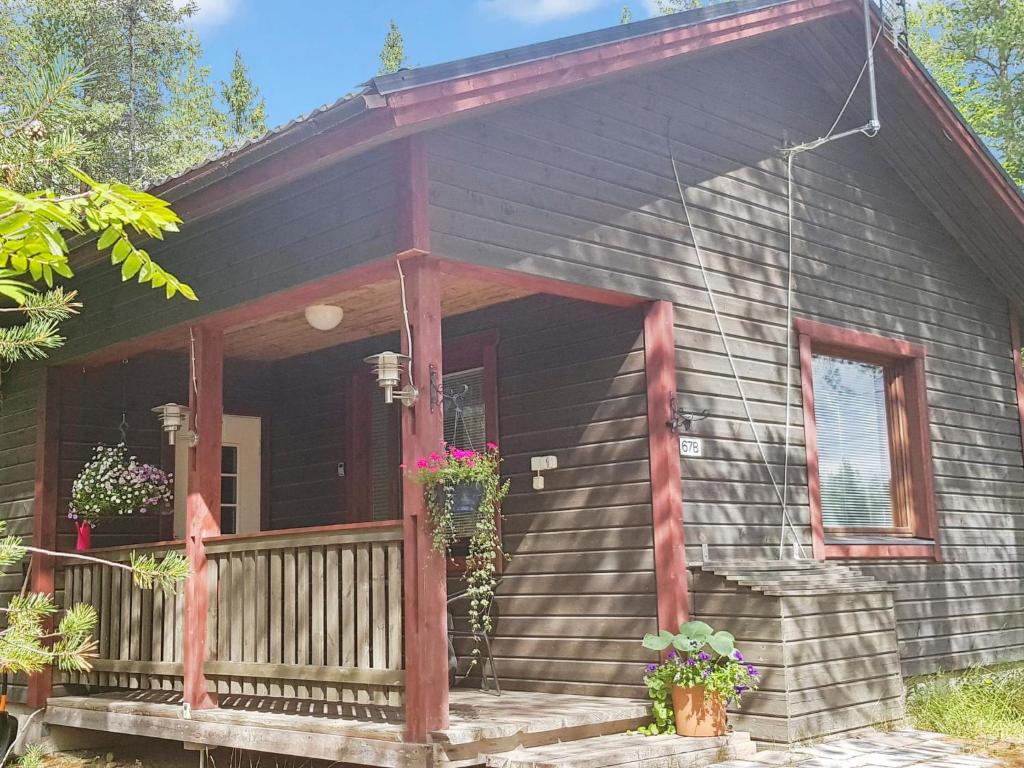 una pequeña casa negra con porche y porche en Holiday Home Kitkan lahti by Interhome en Kesäniemi