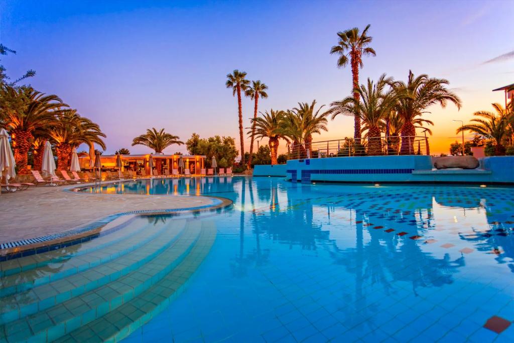 a large swimming pool with palm trees in the background at Lagomandra Hotel and Spa in Lagomandra