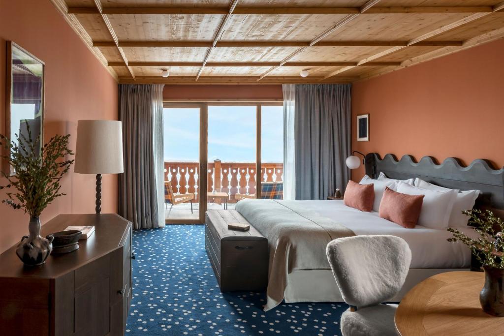 een slaapkamer met een groot bed en een balkon bij Hotel Le Coucou Méribel in Méribel