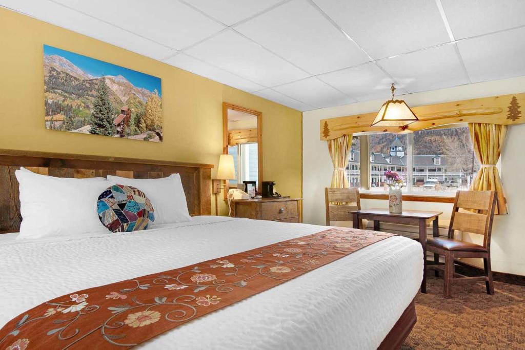 Un dormitorio con una cama y un escritorio y una ventana. en Box Canyon Lodge and Hot Springs, en Ouray
