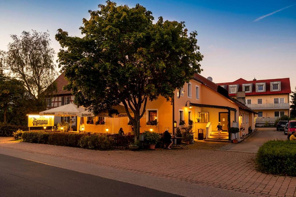 a person sitting under a tree next to a building at Hotel-Gasthof Rangau in Ansbach