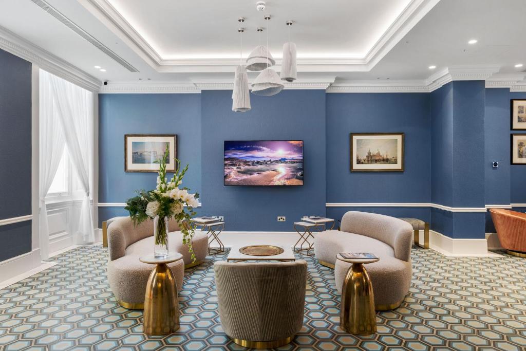 a lobby with blue walls and chairs and a table at Commodore Hotel in London