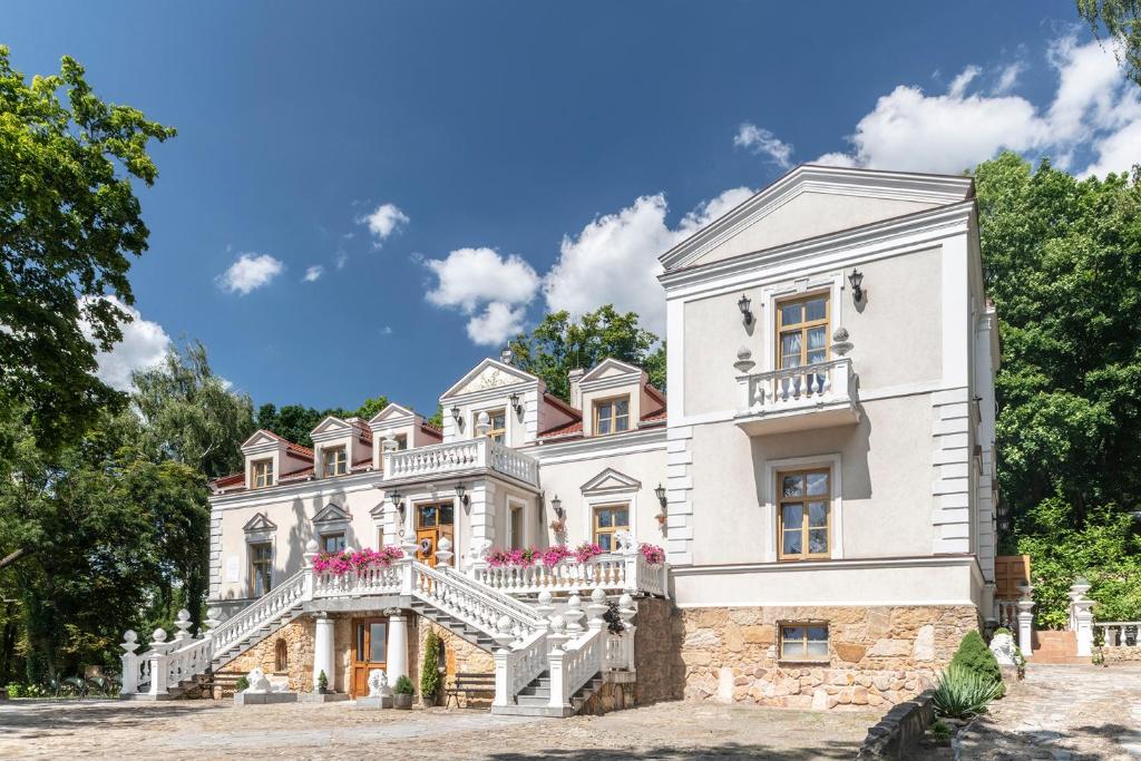 una casa blanca con una escalera delante en Pałac Tarnowskich Hotel & Restauracja & SPA en Ostrowiec Świętokrzyski
