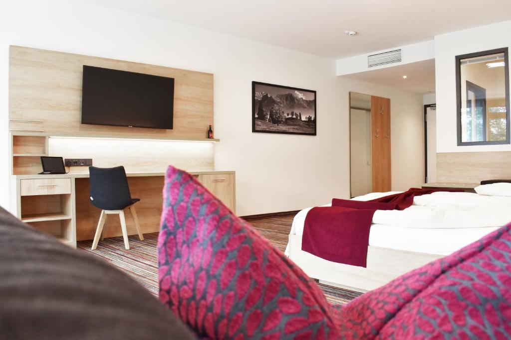 a hotel room with a bed and a tv at Soloplan City Resort in Kempten