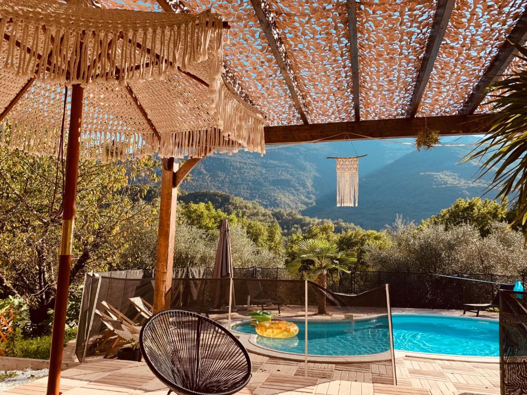 un patio con piscina, sombrilla y silla en Petit 2P au coeur des montagnes en Puget-Théniers