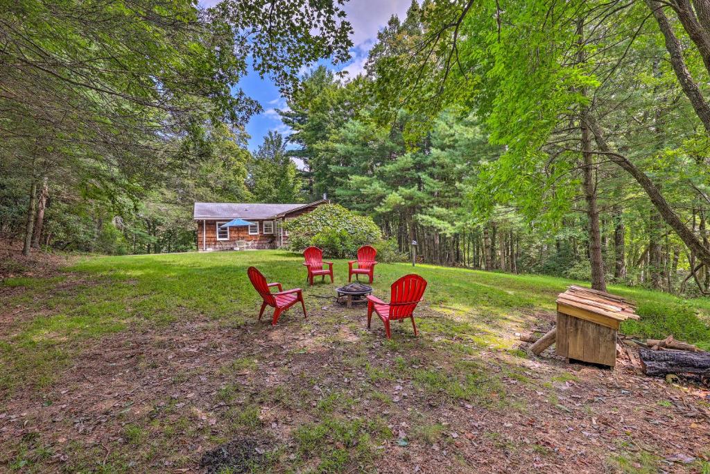 four red chairs in front of a log cabin at Peaceful Roaring Gap Retreat with Fire Pit and Patio! in Roaring Gap