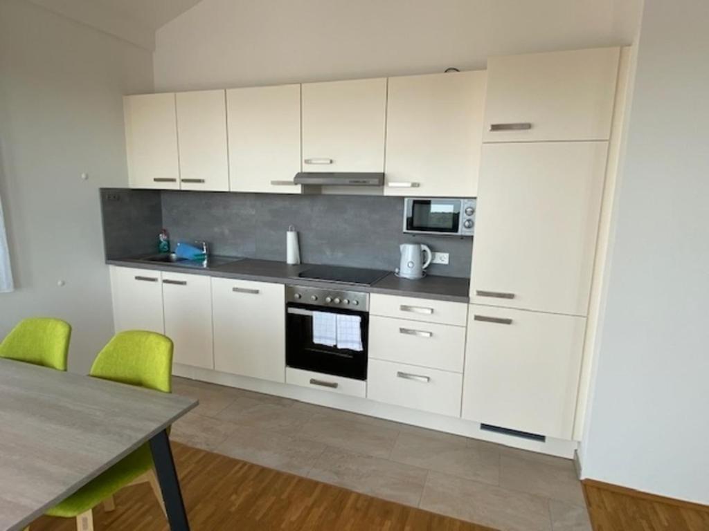 a kitchen with white cabinets and a table with green chairs at Penthouse 34 -rollstuhlgerecht- in Oerlinghausen