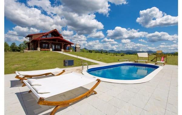 a swimming pool with two lounge chairs and a house at Wooden House Sveti Rok in Sveti Rok