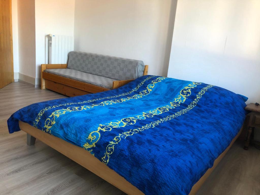 a bed with a blue comforter and a couch at Chambres d'Hotes Le Passiflore in Les Brenets
