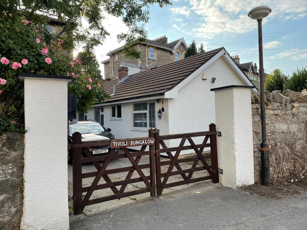 a small white house with a wooden fence at Tivoli Bungalow in Weston-super-Mare