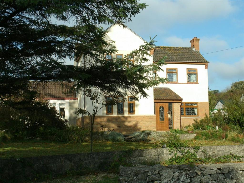 a large white house with a tree in front of it at Ebborways Farm Bed and Breakfast in Priddy