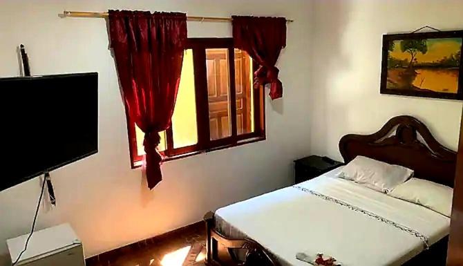 1 dormitorio con 1 cama, TV y ventana en Hostal Selvatrip, en Leticia