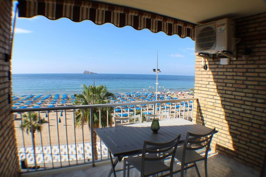 een balkon met een tafel en stoelen en het strand bij RANCHOS 3-2 Levante Beach in Benidorm