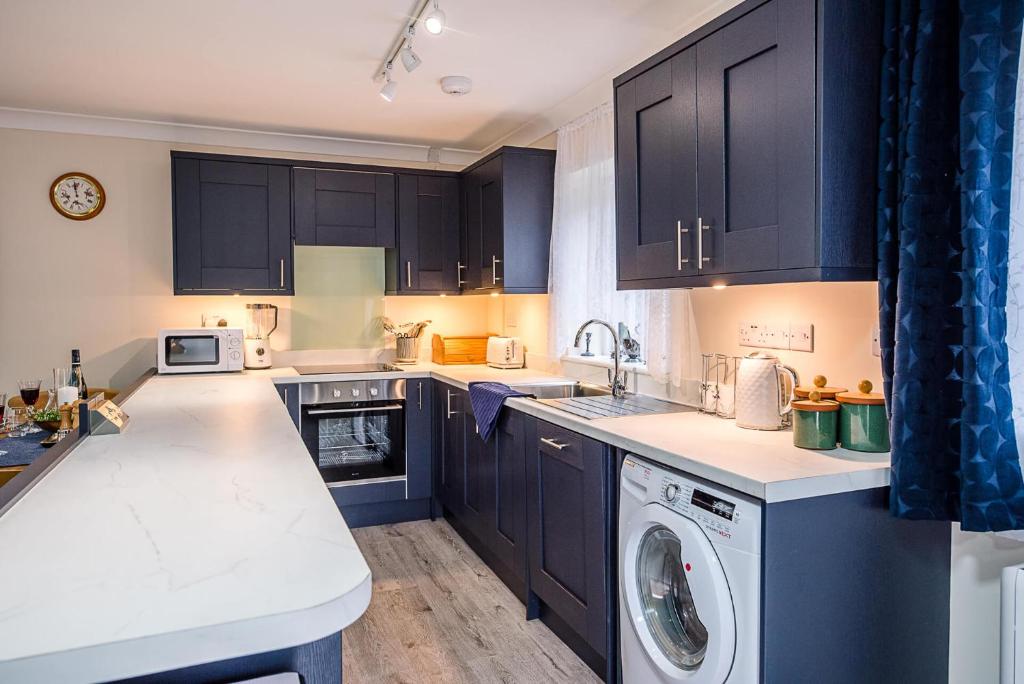 a kitchen with black cabinets and a washer and dryer at Liv's Place Bramfield Air Manage Suffolk in Halesworth