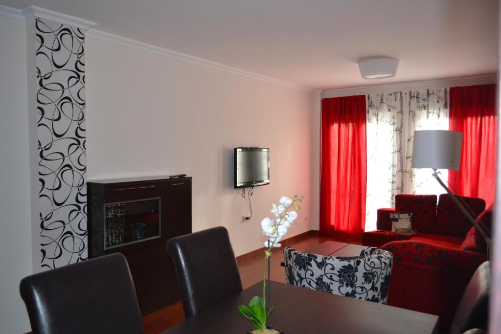 sala de estar con mesa y sofá rojo en Apartamento Acueducto, tres dormitorios y parking gratis, en Mérida