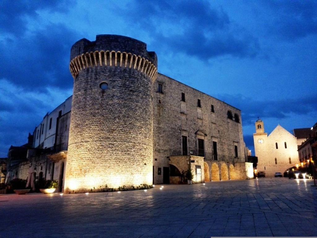 un gran edificio de ladrillo con una torre de reloj por la noche en L'isola di Francesca, en Conversano